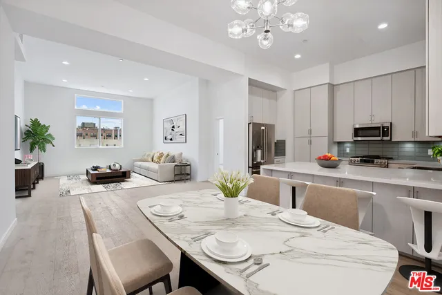 a kitchen with stainless steel appliances kitchen island granite countertop a dining table chairs sink and cabinets