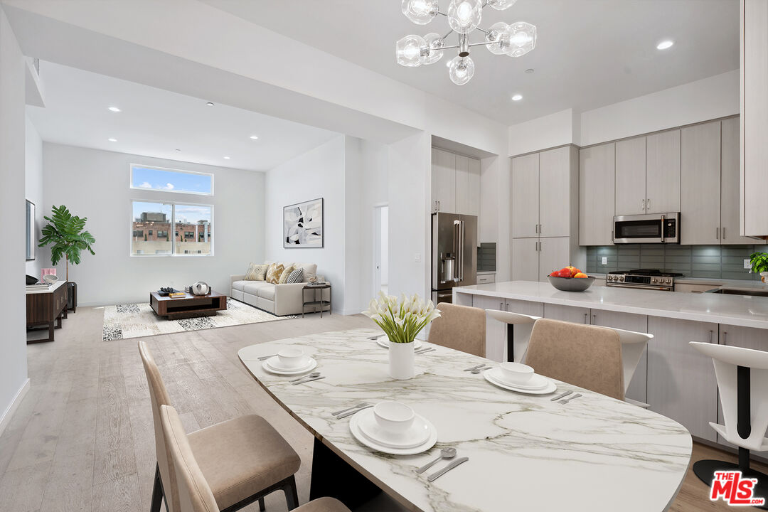 a kitchen with stainless steel appliances kitchen island granite countertop a dining table chairs sink and cabinets