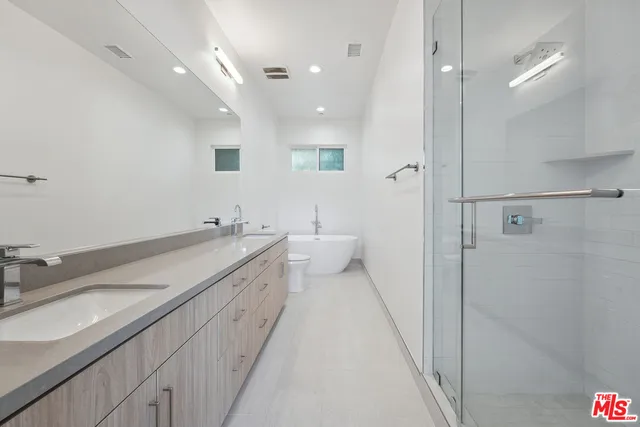 a spacious bathroom with a double vanity sink a mirror and a shower