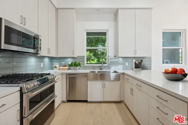 a kitchen with stainless steel appliances white cabinets and a stove top oven