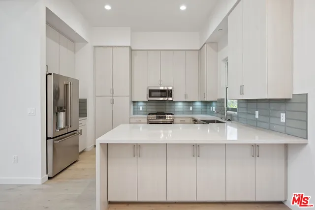 a kitchen with kitchen island a sink stainless steel appliances and cabinets