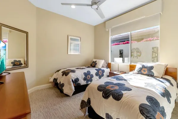 a bedroom with two beds and a ceiling fan
