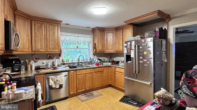 a kitchen with stainless steel appliances granite countertop a refrigerator a sink dishwasher a stove with wooden cabinets and floor