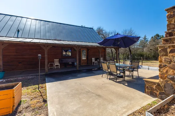 a view of a patio with a table and chairs under an umbrella with wooden fence