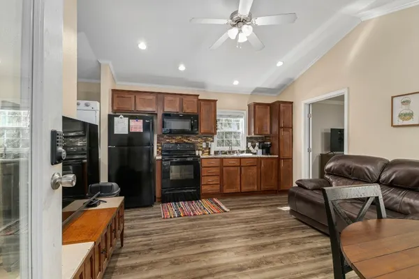 a kitchen with stainless steel appliances kitchen island granite countertop a refrigerator a stove a sink dishwasher a dining table and chairs with wooden floor