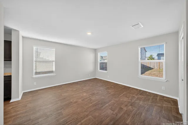 a view of an empty room with a window and wooden floor