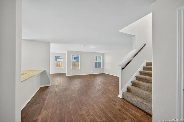 a view of a livingroom with wooden floor and stairs