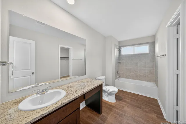 a bathroom with a granite countertop sink a toilet and shower