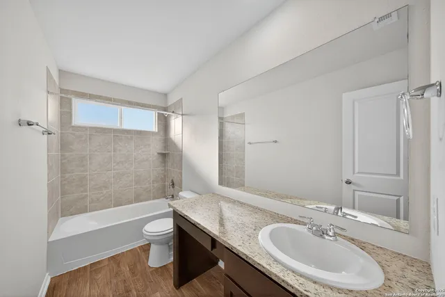 a bathroom with a granite countertop sink a toilet and shower