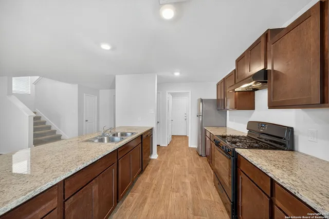 a kitchen with stainless steel appliances granite countertop a stove a sink and a refrigerator