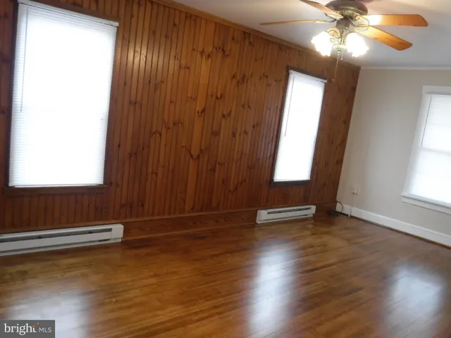an empty room with wooden floor fan and windows