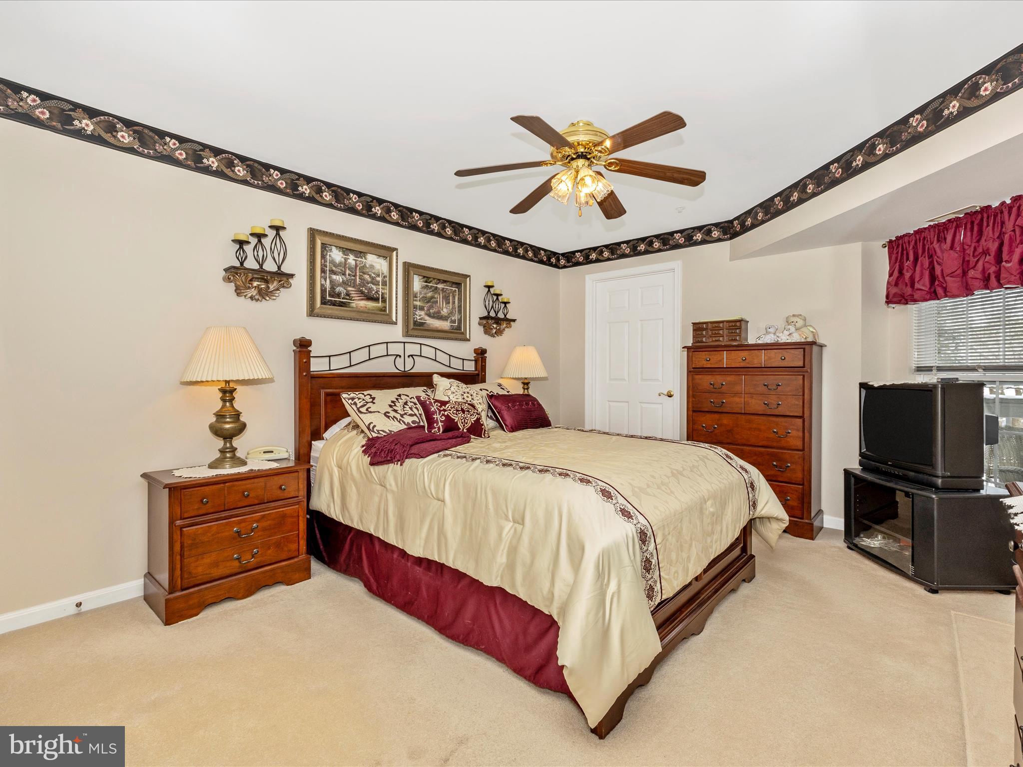 2501 Coach House Way, Unit 2C Frederick, MD 21702 - Photo 25 of 54 a bedroom with a bed a chandelier and a flat screen tv