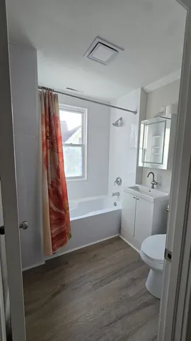 a bathroom with a sink a toilet a window and a mirror