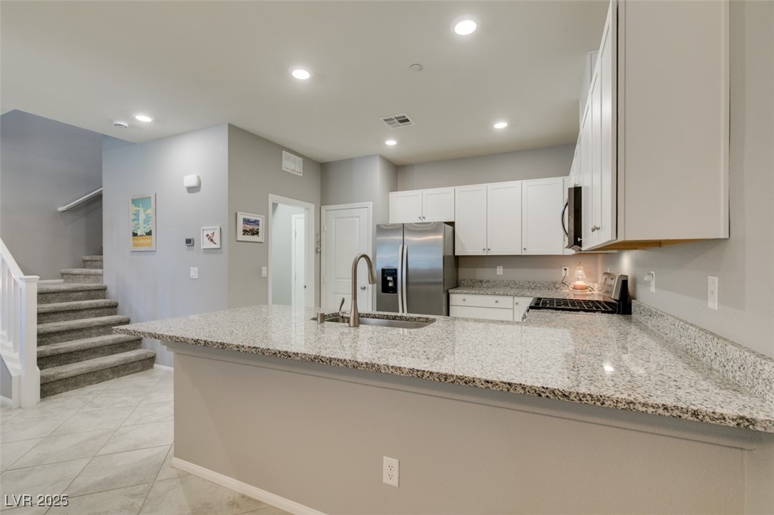 2870 Turnstone Ridge Street Henderson, NV 89044 - Photo 20 of 50 Kitchen featuring stainless steel appliances, a sink, a peninsula, light stone counters, and recessed lighting