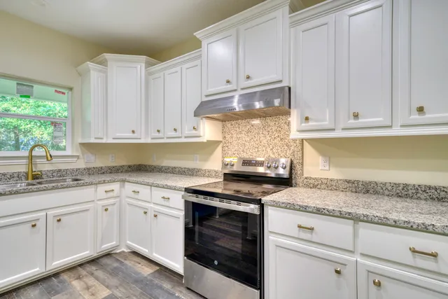 a kitchen with granite countertop stainless steel appliances white cabinets granite counter tops and a wooden floors