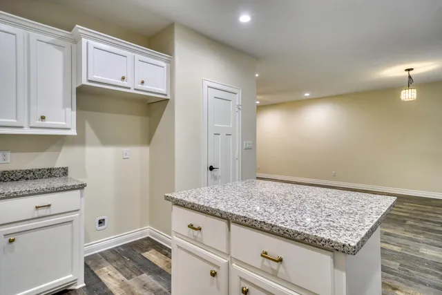 a view of kitchen with granite countertop white cabinets and white appliances