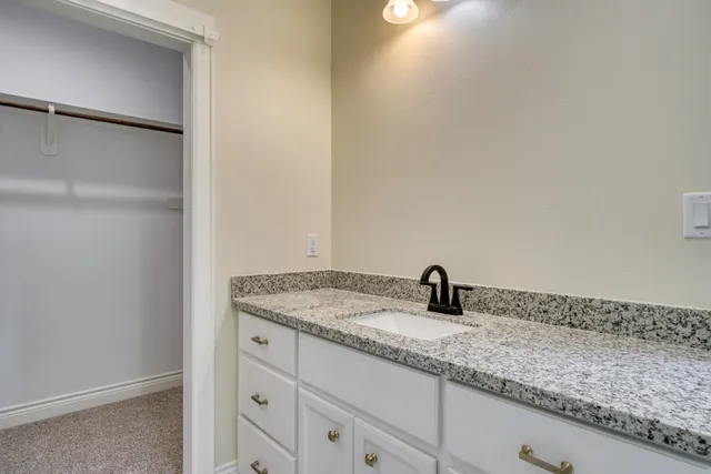 a bathroom with a granite countertop sink and a mirror