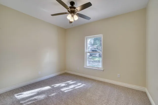 an empty room with a window and a fan
