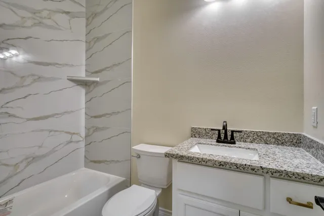 a bathroom with a granite countertop sink toilet and mirror