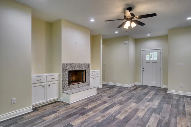 a view of a livingroom with a fireplace a chandelier fan and wooden floor