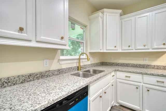 a kitchen with granite countertop a sink and white cabinets