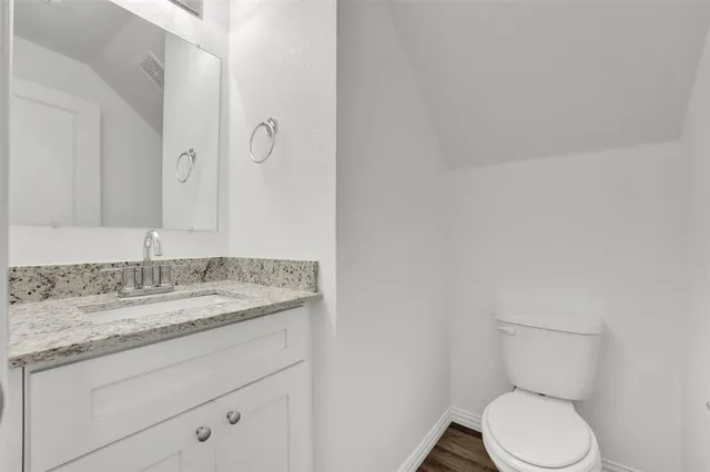a bathroom with a granite countertop toilet and a sink