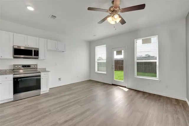a view of an empty room with a kitchen and a stove top oven