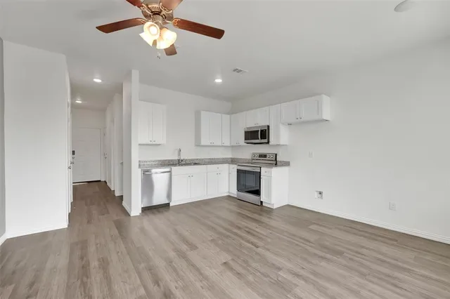 a kitchen with stainless steel appliances white cabinets and wooden floor