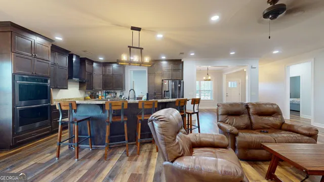 a kitchen with stainless steel appliances granite countertop a refrigerator a sink dishwasher a dining table and chairs with wooden floor