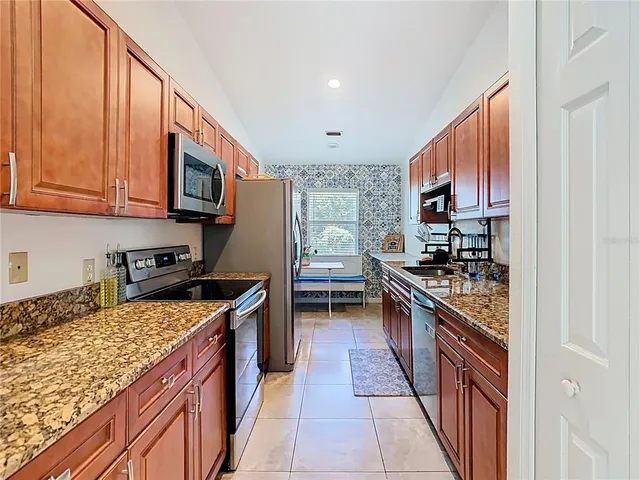a kitchen with stainless steel appliances granite countertop a stove top oven a sink dishwasher and a microwave oven with cabinets