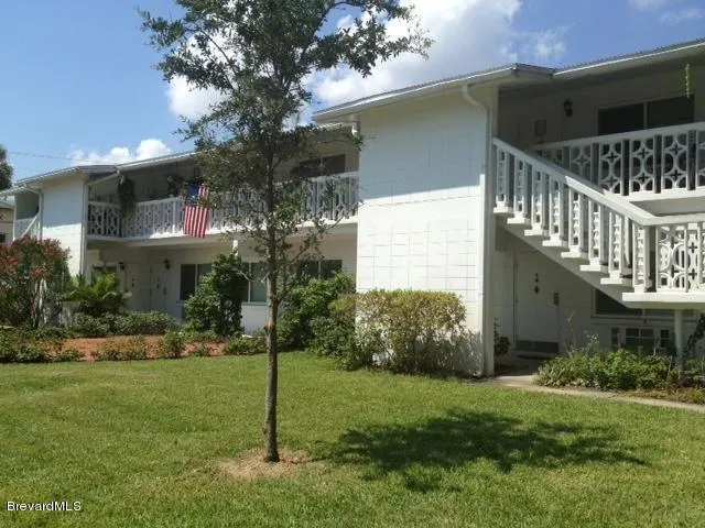 a view of a house with brick walls and a yard with plants