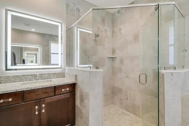 a bathroom with a granite countertop sink and shower