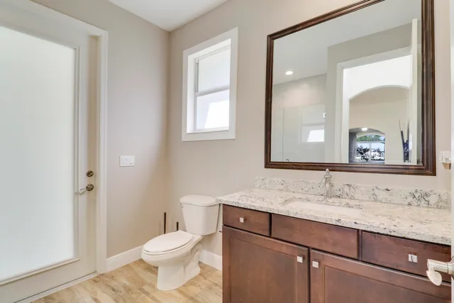 a bathroom with a granite countertop sink toilet and mirror