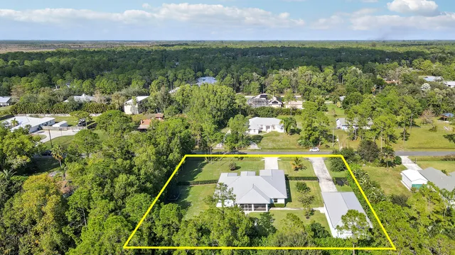 an aerial view of a residential houses with outdoor space and trees