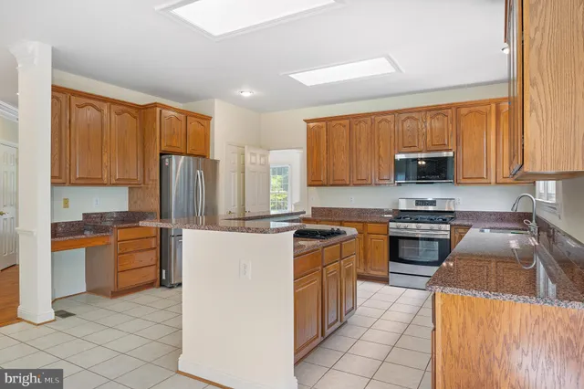 a view of an empty room with wooden floor and a ceiling fan