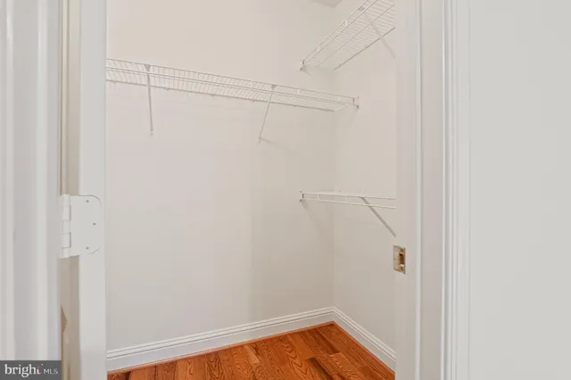 a view of an empty room with wooden floor and a ceiling fan