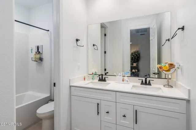 a bathroom with a double vanity sink toilet and shower