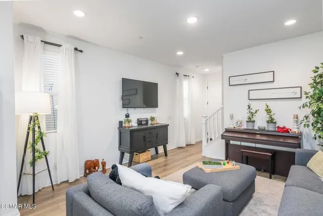 a living room with furniture a flat screen tv and a chandelier