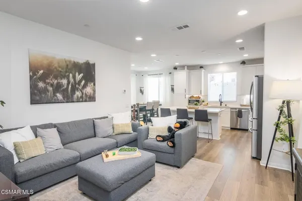 a living room with furniture and kitchen view with wooden floor