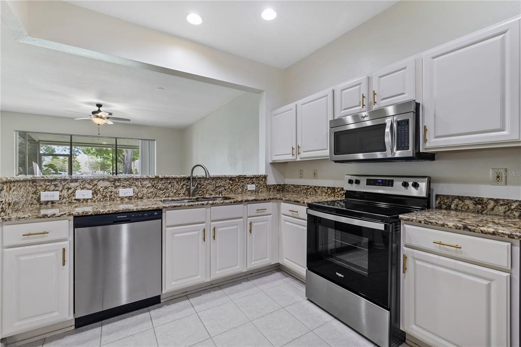 8520 Sandy Beach Street Tampa, FL 33634 - Photo 3 of 25 a kitchen with stainless steel appliances granite countertop a stove top oven microwave and cabinets