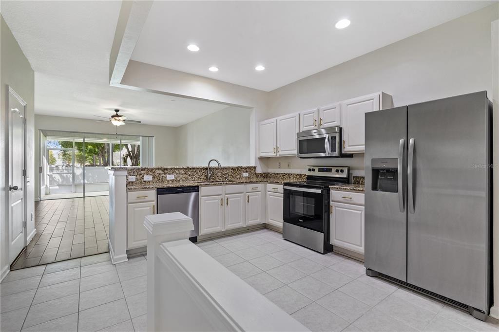 8520 Sandy Beach Street Tampa, FL 33634 - Photo 4 of 25 a kitchen with kitchen island granite countertop stainless steel appliances refrigerator sink and cabinets
