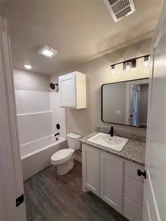 a bathroom with a granite countertop sink toilet and mirror