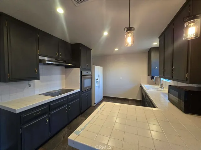 a kitchen with granite countertop a sink a counter top space stainless steel appliances and cabinets