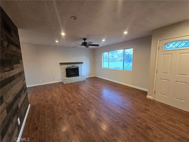 an empty room with windows fireplace and wooden floor