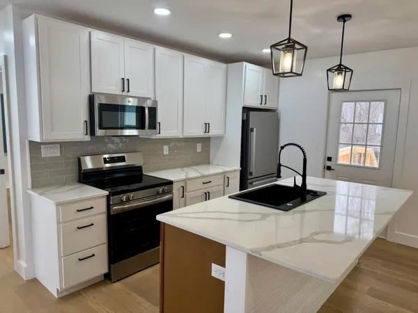 a kitchen with stainless steel appliances kitchen island a white stove top oven and cabinets