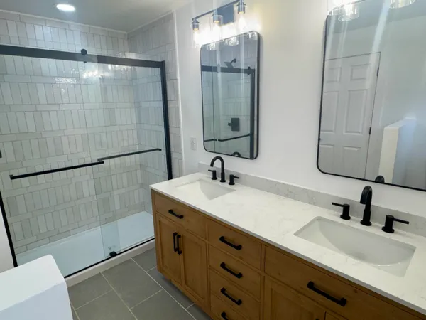 a bathroom with a double vanity sink mirror and shower