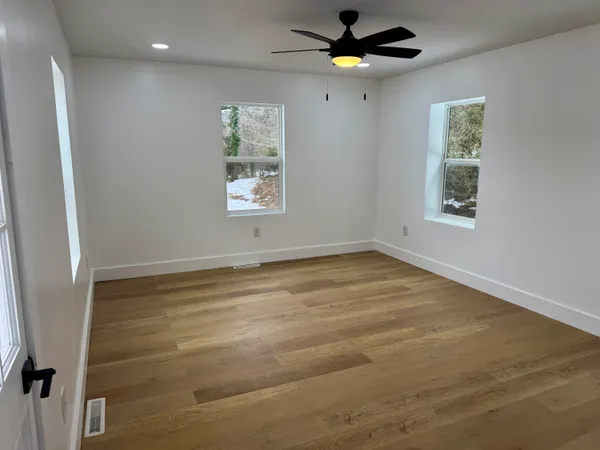 an empty room with windows and fan