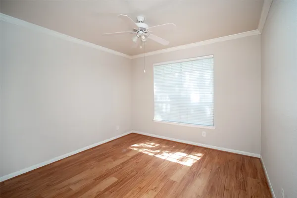 an empty room with wooden floor chandelier fan and windows
