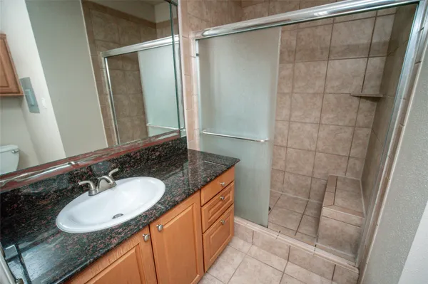 a bathroom with a granite countertop sink a mirror and a shower
