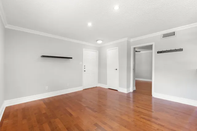 a view of an empty room with wooden floor and a window